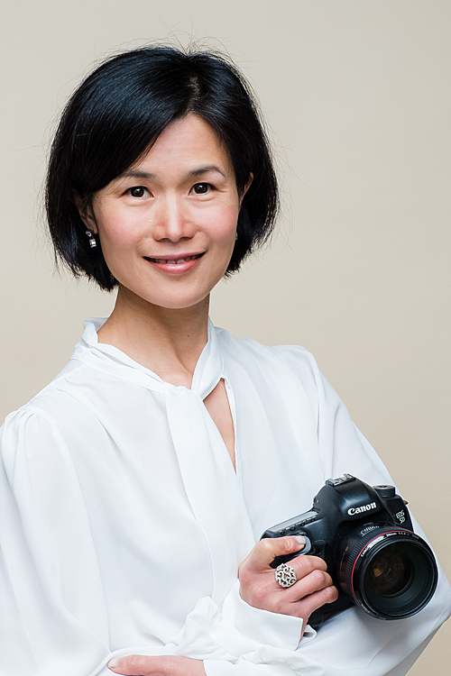 female-photographer-london-in-white-shirt-holding-camera-smiling
