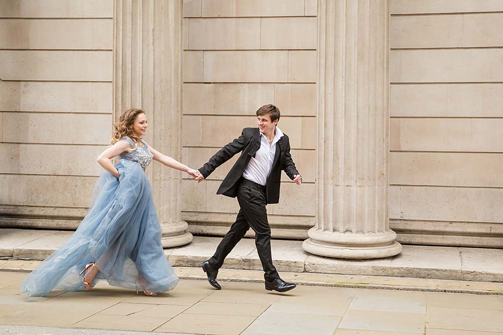 couple-photography-central-london-man-running-with-woman-in-tux-and-ball-gown-holding-hand-romantically-eloping