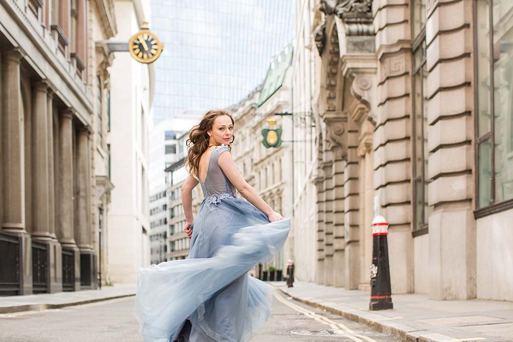 beautiful-blonde-hair-woman-in-blue-elegant-ball-gown-swirling-in-central-London-city-area-in-front-of-victorian-building