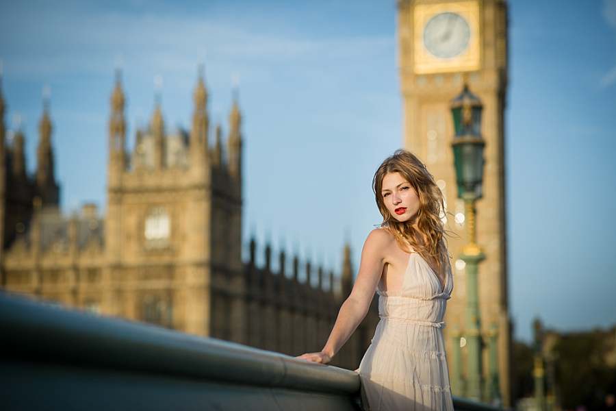 Woman in a white dress posing on Westminster Bridge with Big Ben in the background with this tourist site being among popular London photo spots