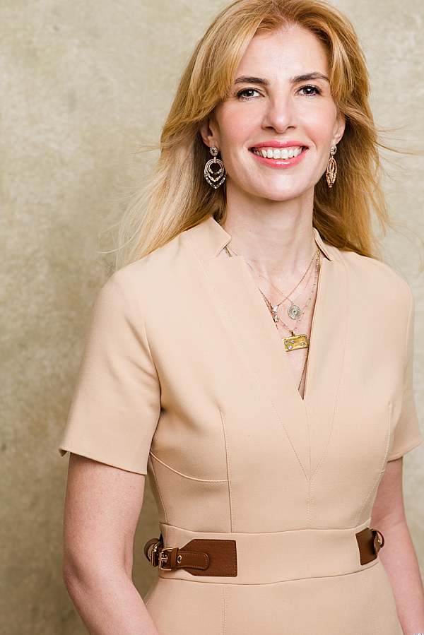 A confident woman in a beige dress smiling, photographed for business portrait and personal branding by a professional photographer in London.